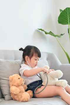 亚洲女孩玩婴儿娃娃玩具亚洲女孩持有听诊器手检查婴儿娃娃玩具