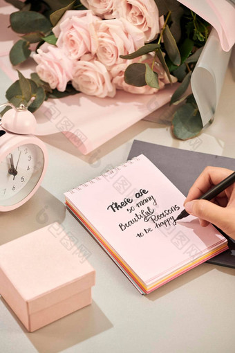女人手持有笔准备好了写粉红色的玫瑰笔礼物粉红色的心白色表格爱概念圣情人节一天概念母亲的一天概念