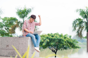 年轻的男人。坐着移动PC大学建筑