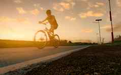 运动模糊体育男人。骑自行车速度运动路晚上日落天空夏天户外锻炼健康的快乐生活骑自行车的人骑山自行车自行车车道