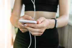 现代小工具培训首页女人健身应用程序智能手机在室内首页健身跟踪器智能手机手耳机体育运动看锻炼健身生活方式概念在线学费
