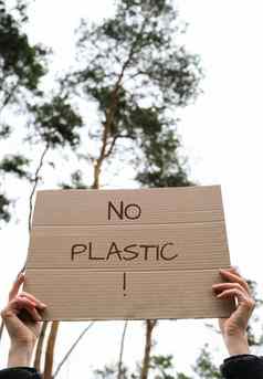 女手持有纸板文本塑料在户外自然背景抗议者积极分子