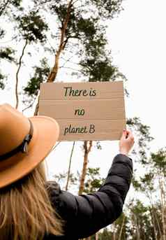 女手持有纸板文本地球在户外自然背景抗议者积极分子
