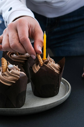 女手使美味的巧克力纸杯蛋糕奶油黑暗背景巧克力松饼生日蛋糕聚会，派对准备