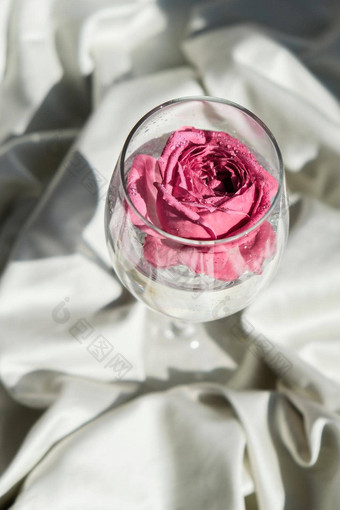 酒玻璃填满粉红色的花petalson<strong>白色丝绸</strong>织物最小的现代生活假期概念情人节女士一天<strong>背景</strong>设计