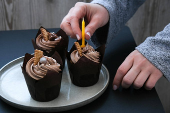 女手使美味的巧克力纸杯蛋糕奶油黑暗背景巧克力松饼生日蛋糕聚会，派对准备