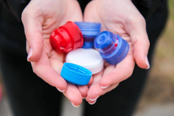 特写镜头高加索人女手完整的色彩斑斓的塑料瓶杯一些浪费塑料盖子回收收集瓶<strong>帽</strong>
