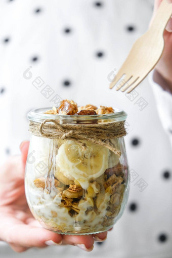 女手女人吃健康的早餐燕麦片格兰诺拉麦片希腊酸奶坚果香蕉牛奶什锦早餐罐子光背景素食主义者素食者重量损失饮食概念<strong>排</strong>毒<strong>菜单</strong>