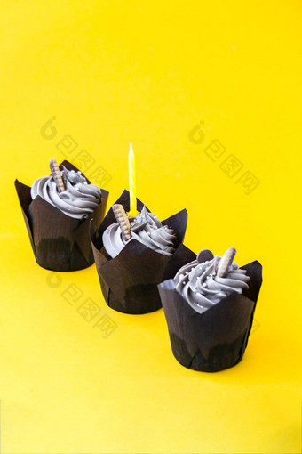 美味的巧克力纸杯蛋糕奶油蜡烛黄色的背景巧克力松饼生日蛋糕聚会，派对
