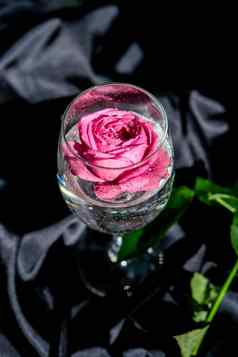 酒玻璃填满粉红色的花petalson表格黑色的丝绸织物最小的现代生活假期概念情人节女士一天背景设计