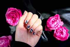 爱词指甲修指甲持有粉红色的玫瑰花黑色的丝绸织物最小的平躺自然女手爱