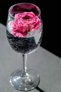 酒玻璃填满粉红色的花petalson表格黑色的最小的现代生活假期概念情人节女士一天背景设计