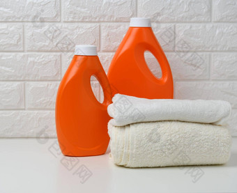 橙色塑料瓶液体洗粉折叠毛巾白色架子上