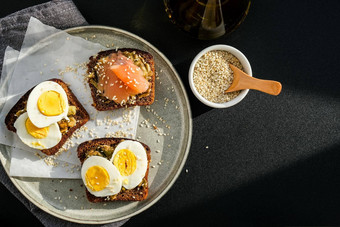烤面包挖走鸡蛋鳄梨大马哈鱼鳄梨色拉酱三明治健康的早餐橄榄石油芝麻种子素食者健康的吃