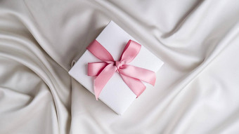 礼物盒子粉红色的丝带<strong>白色</strong>织物<strong>丝绸背景</strong>前视图最小的现在复制空间