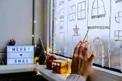 女手吸引了圣诞节假期装饰窗口玻璃年风景城市建筑花环灯舒适装饰圣诞节概念