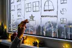 女手吸引了圣诞节假期装饰窗口玻璃年风景城市建筑花环灯舒适装饰圣诞节概念