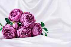 花束美丽的紫罗兰色的牡丹白色丝绸织物背景复制空间问候卡
