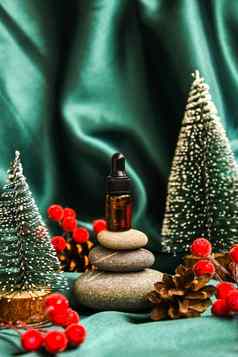 小瓶血清堆栈玄武岩石头圣诞节装饰绿色缎织物背景时尚的颜色美吸管下降金字塔鹅卵石