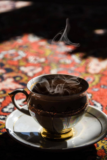 古董瓷茶时间土耳其地毯黑色的茶烟中国杯飞碟阳光热蒸汽
