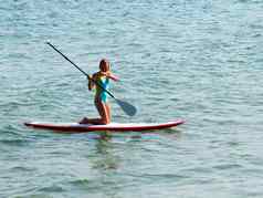 十几岁的女孩骑sup-board海膝盖