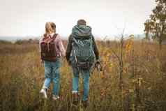 徒步旅行秋天自然夫妇背包客使场后视图男人。女人背包徒步旅行波兰人走自然在户外徒步旅行概念