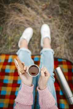 野餐零食自然女手持有杯茶三明治年轻的女人青少年女孩吃零食坐着草特写镜头拍摄高角视图