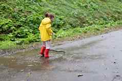 好玩的女孩穿黄色的雨衣跳水坑降雨