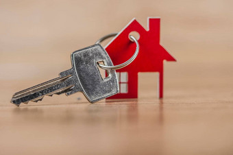 关键房子形状的钥匙链安排木背景真正的房地产保险概念抵押贷款买出售房子房地产经纪人概念