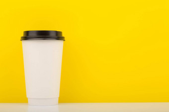 白色高纸板杯咖啡茶白色表格黄色的背景复制空间