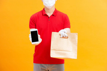 年轻的交付男人。医疗手套保护脸面具持有聪明的电话复制空间购物袋手