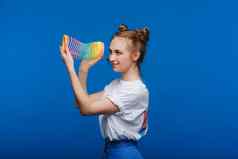 美丽的年轻的女孩玩彩虹紧身的玩具童年蓝色的背景