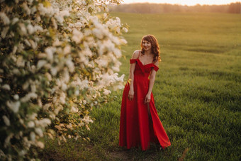 女孩红色的衣服红色的嘴唇站大白色开花树日落