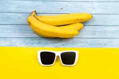 黄色的香蕉太阳镜谎言蓝色的木背景黄色的背景