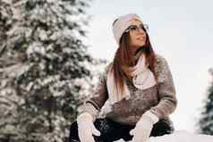 女孩毛衣眼镜冬天坐在白雪覆盖的背景森林