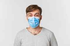 概念流感大流行科维德社会距离特写镜头惊讶男人。医疗面具提高眉毛惊讶站白色背景
