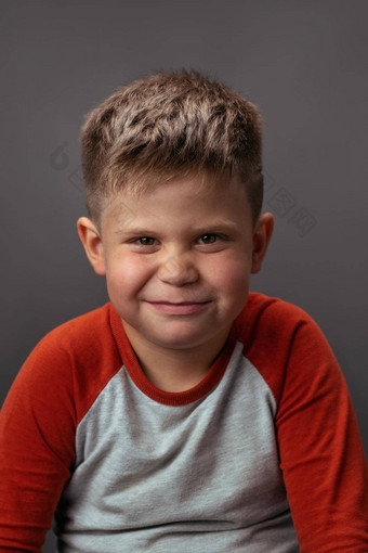 学前教育男孩微笑得意的笑相机肖像有趣的孩子灰色的背景情绪概念