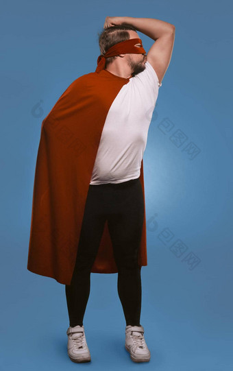 超级英雄男人。准备好了保存世界男人。显示吻肌肉站红色的超级英雄面具外套减少褪了色的牛仔布蓝色的背景