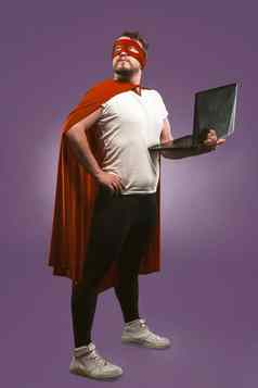 超级英雄男人。持有移动PC深思熟虑业务男人。红色的超级英雄服装电脑摆姿势葡萄紫色的背景快互联网概念