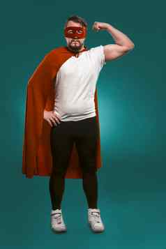 超级英雄男人。显示肌肉准备好了保存世界男人。红色的超级英雄面具外套显示肌肉相机减少比斯开湾绿色背景