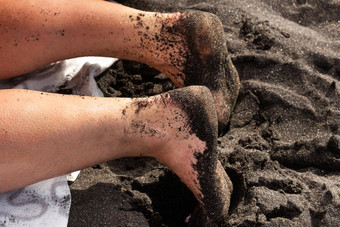 特写镜头女人的腿脚沙子说谎火山黑色的沙子海滩tenerife