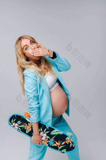 怀孕了女孩绿松石衣服滑板手灰色的背景