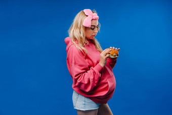 怀孕了女孩粉红色的衣服汉堡手蓝色的背景