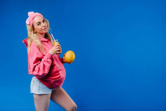 怀孕了女孩粉红色的衣服瓶汁瓜蓝色的背景