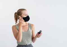 年轻的女人保护面具持有无线耳塞