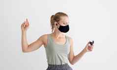 年轻的女人保护面具持有无线耳塞跳舞