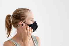 年轻的女人保护面具持有无线耳塞