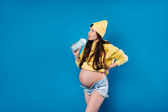 怀孕了女孩黄色的衣服玻璃汁蓝色的背景