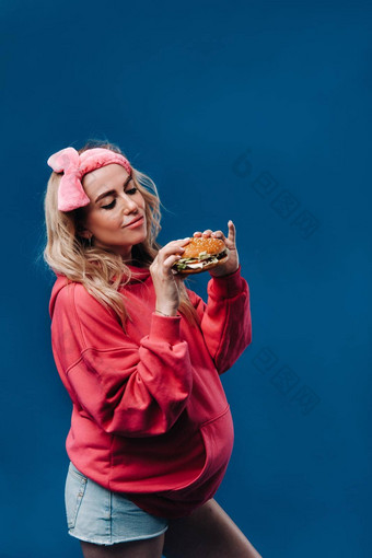 怀孕了女孩粉红色的衣服汉堡手蓝色的背景