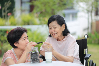 女儿有爱心的上了年纪的亚洲女人挑选巧克力饼干妈妈。后院
